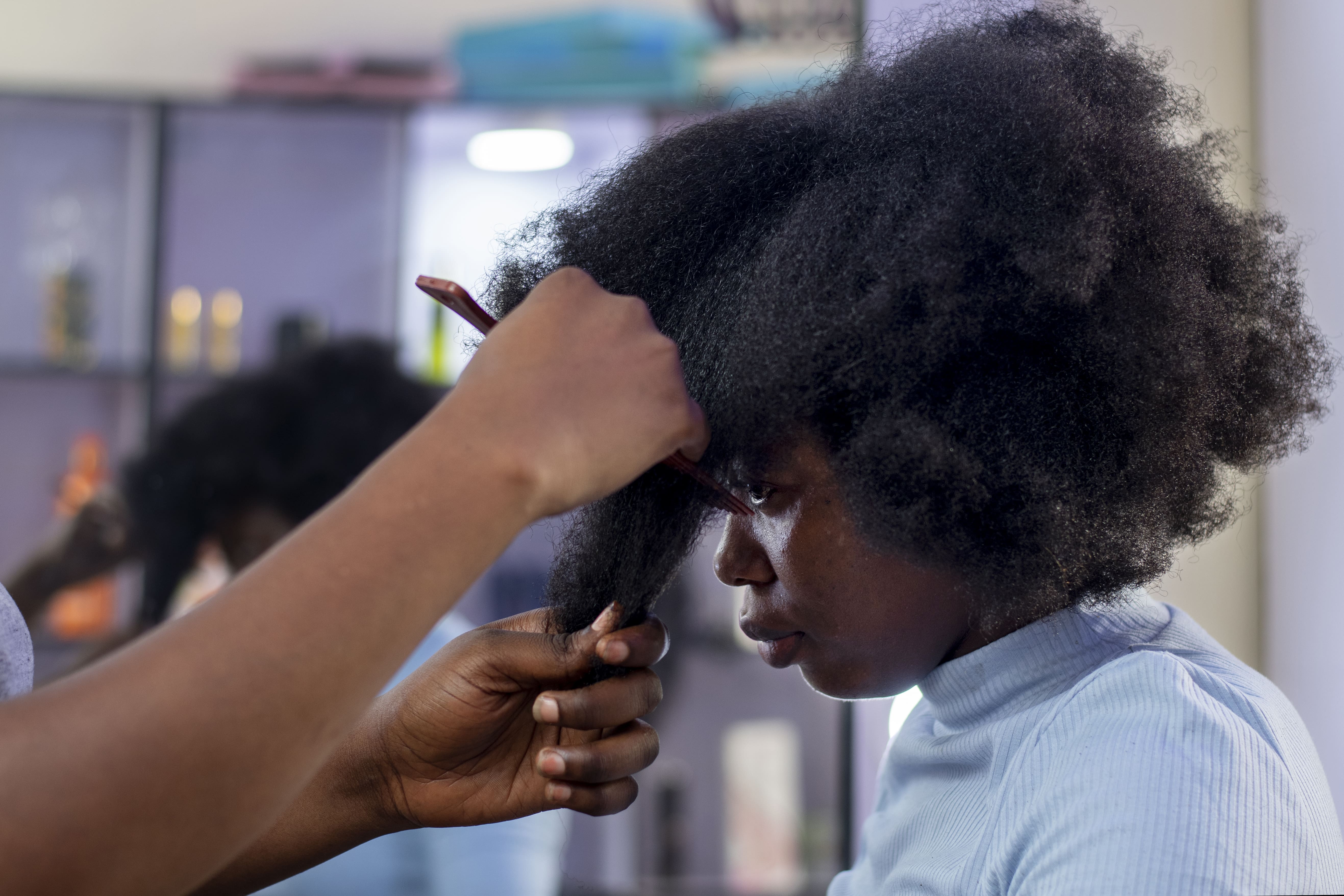 stylist woman taking care her client afro hair